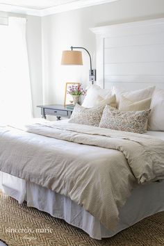 a bed with white sheets and pillows in a bedroom