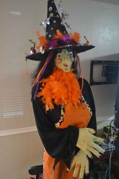 a woman dressed in an orange and black witch costume with her hands on her chest