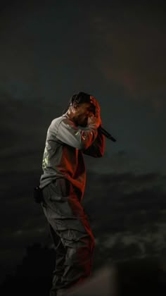 a man standing on top of a roof holding a baseball bat in his hand and looking at the sky