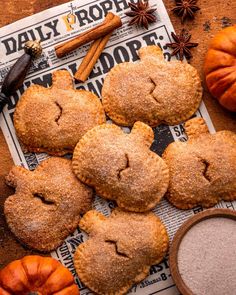 several pumpkin pies on top of a newspaper next to spices and an orange cup