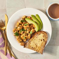 a plate with bread, avocado and some type of meat on it next to a cup of coffee