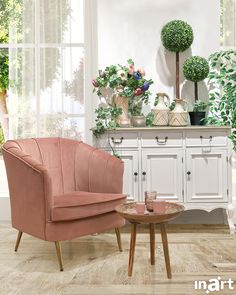 two pink chairs sitting next to each other in front of a white cabinet with potted plants