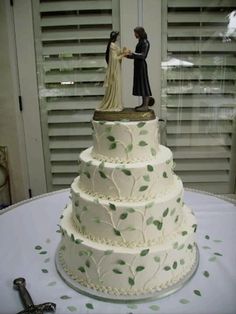 a wedding cake with figurines on top is displayed in front of shutters