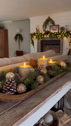 a wooden tray filled with candles on top of a table next to a fire place