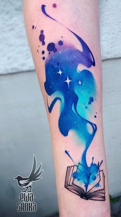 a woman's arm with a book and stars on it, painted in blue