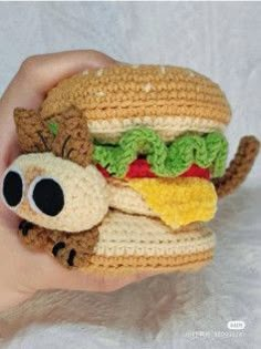 a hand holding a small crocheted sandwich with a cat on it's face