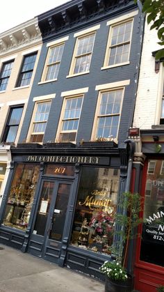 a store front with many windows and flowers in the planter on the sidewalk next to it