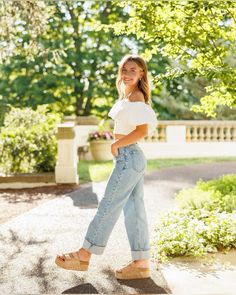 a woman in white shirt and jeans walking