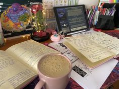 a cup of coffee sitting on top of a desk next to an open book