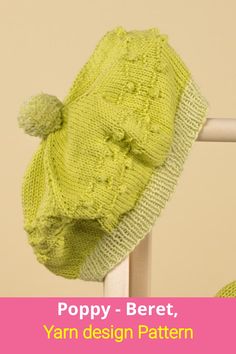 a green knitted hat sitting on top of a white rail next to a wall