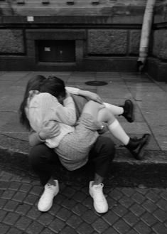 black and white photograph of two people sitting on the ground with their arms around each other