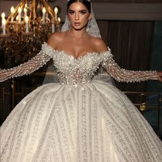 a woman in a wedding dress standing next to a chandelier