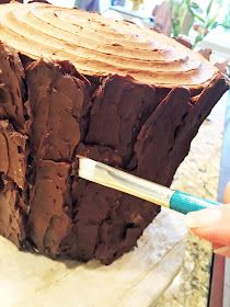 a person holding a brush in front of a large piece of chocolate cake on a counter