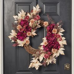 a wreath with dried flowers is hanging on the front door to give it a warm welcome