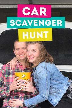 a man and woman sitting in the back of a pick up truck holding popcorn buckets