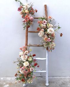 an old ladder decorated with flowers and greenery