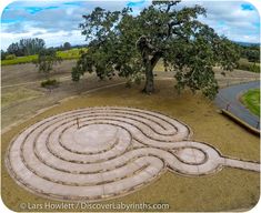 an aerial view of a stone maze in the middle of a field with a tree