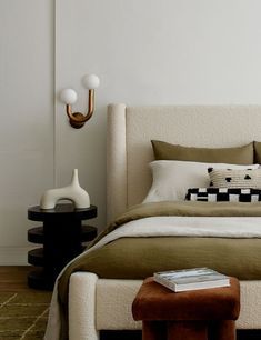 a bed with pillows and blankets in a bedroom next to a wall mounted light fixture