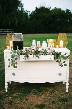 a table with candles and flowers on it in the middle of a grassy area next to a field