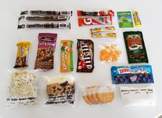 an assortment of snacks laid out on top of a white table with candy bars and crackers