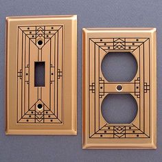 two light switch plates sitting next to each other on a gray surface with black and white designs