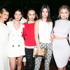 four women standing next to each other in front of a crowd at a fashion show