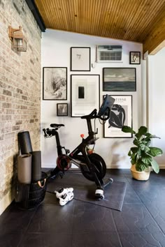 an indoor exercise bike in the corner of a room with pictures on the wall above it