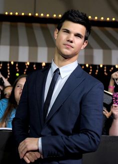 a man in a suit and tie standing next to a group of people