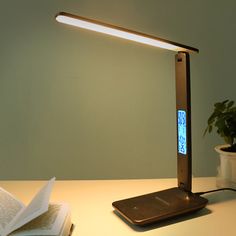 a desk lamp that is on top of a table with an open book next to it