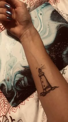 a woman's arm with a small lighthouse tattoo on her left forearm and wrist