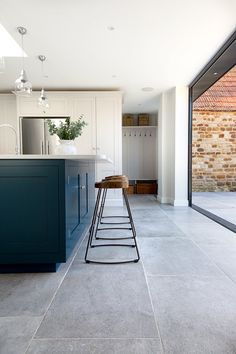 a kitchen with blue cabinets and stools next to an open floor plan that has glass doors on both sides