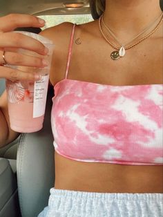 a woman sitting in the back seat of a car holding up a bottle with liquid