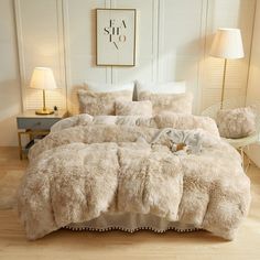 a bed with white fur on it and two lamps next to it in a room