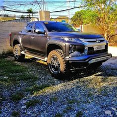 a grey truck parked on top of a gravel road