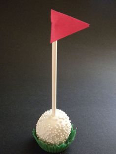 a cupcake with a red flag sticking out of it's side on a black surface