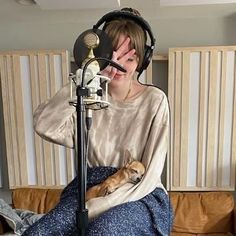 a person sitting on a couch with a cat in their lap and headphones over their ears