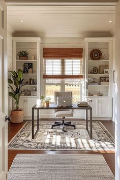 a home office with white walls and wooden floors, along with an area rug on the floor