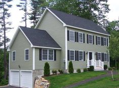 a two story house with green siding and white shutters