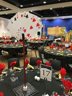 the tables are set up for a casino themed event with black tablecloths and red centerpieces