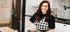 a woman standing in a kitchen preparing food