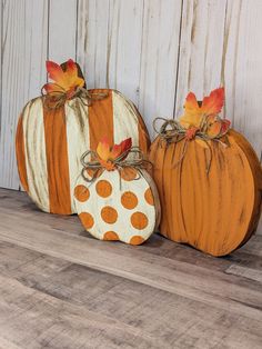 three painted pumpkins sitting on top of a wooden table