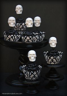 cupcakes with white frosting and black icing are arranged in the shape of skulls