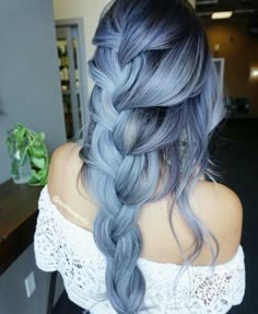 a woman with blue hair is shown from the back and has long braids in it