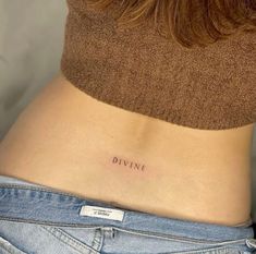 a woman's lower back with the word divine tattooed on her left side ribcage