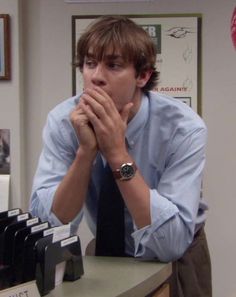 a man sitting at a desk with his hands clasped to his face, in an office setting