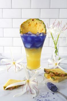 a blue and yellow drink sitting on top of a table next to some white flowers