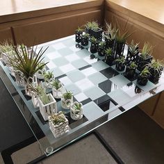 a glass table topped with potted plants on top of a checkered board