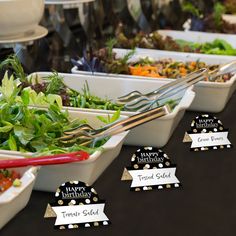 there are many different types of salads on the buffet table with name tags in front of them