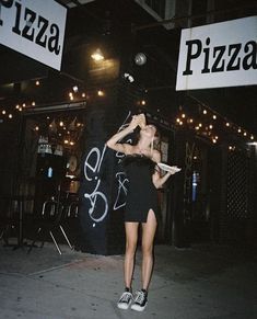 a woman standing in front of a pizza shop holding a piece of paper and talking on the phone