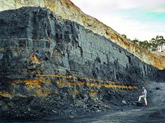 a man standing next to a large pile of rocks on top of a dirt field